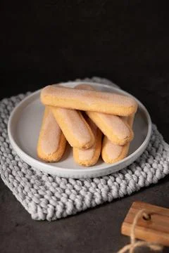 Stack of Ladyfinger Biscuits on White Plate with Knitted Coaster 스톡 사진