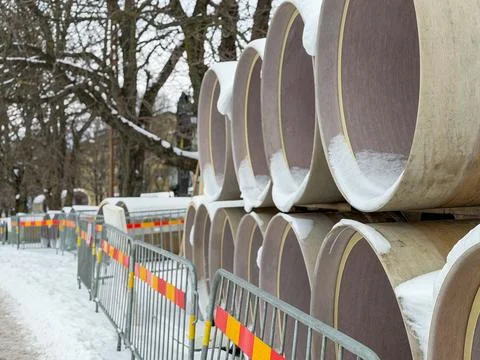 Stack of large pre insulated pipes at snowy railway construction area Stock Photos