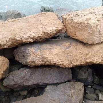 Stack of large rectangular weathered rocks forming coastal defense Stock Photos