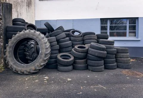 Stack of large used tractor and truck tires near an industrial wall surface 库存照片