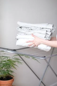 Stack of laundry and woman folding clean bedding and clothes Stock Photos