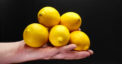 A stack of lemons being held by man showing them off isolated on black Stock Footage 205435055