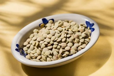 Stack of lentils on a plate on a yellow background, view from above 스톡 사진