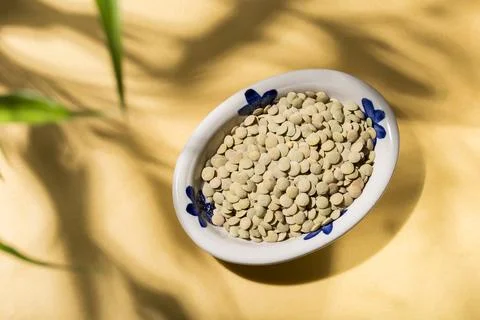 Stack of lentils on a plate on a yellow background, view from above Stock Photos