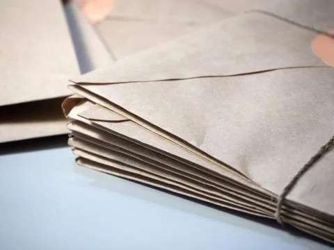 A stack of letters in Kraft envelopes lies on the table tied with string Stock Photos