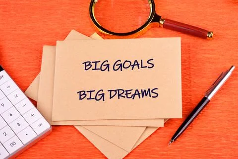 A stack of light brown envelopes shows BIG GOALS BIG DREAMS on an orange surf 스톡 사진