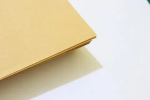 Stack of Light Brown Paper Resting on a Clean White Surface Casting a Soft .. Stock Photos