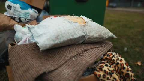 A stack of linens, bedding, and stuffed toys rests on a heap of garbage Stock Footage 272436646