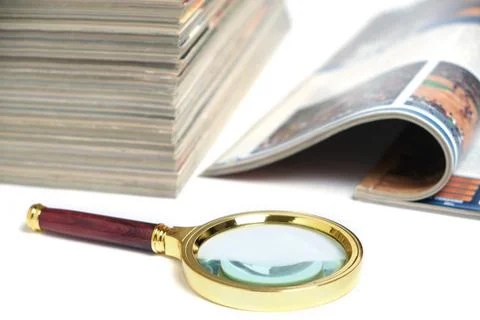 Stack of magazines and magnifying glass on white background.Concept of lear.. Stock Photos