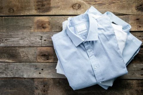 Stack of male folded shirts on rustic background Stock Photos