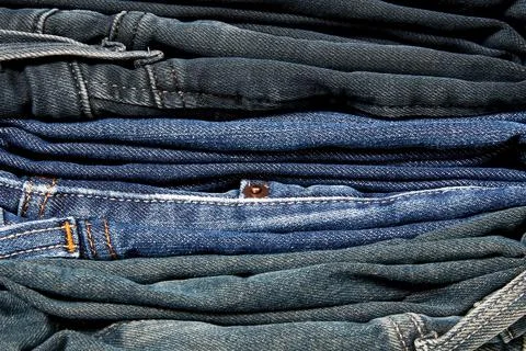 Stack of many blue jeans on the clothes shop shelf Stock Photos