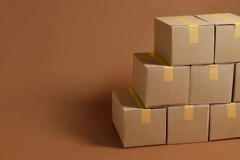 Stack of many cardboard boxes on brown background, space for text Stock Photos