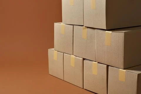 Stack of many cardboard boxes on brown background, space for text Stock Photos