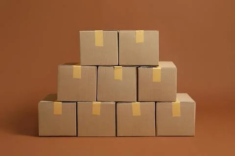 Stack of many cardboard boxes on brown background Stock Photos