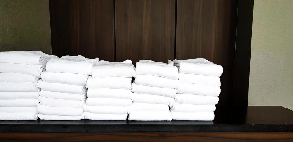 Stack of many clean white towel putting on the black shelf with wooden wall Stock Photos