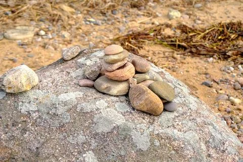 Stack of many small pebbles on top of the big grey round stone laying on pebb Stock Photos
