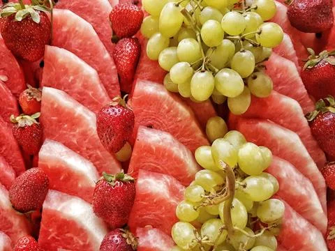 Stack of many watermelon slices, grapes and strawberries Stock Photos