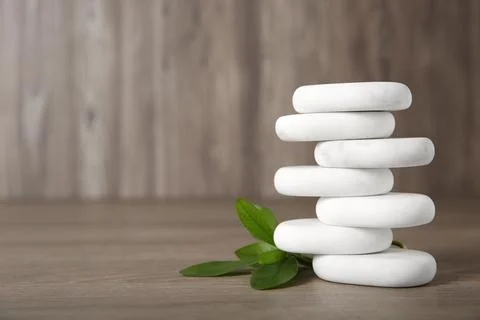 Stack of marble spa stones with branch on wooden background. Space for text Foto stock