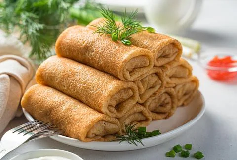 A stack of meat-stuffed pancakes with fresh dill and onions on a white plate  Stock Photos