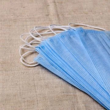 A stack of medical masks on a light-colored cloth. Stock Photos