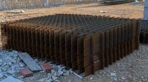 Stack of metal grating resting on a construction site at midday amid ongoin.. Stock Photos