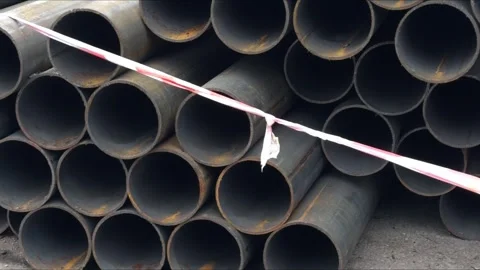 A stack of metal pipes of various diameters is piled at a construction site Stock Footage 324814403