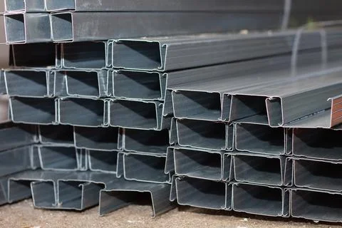 A stack of metal profiles for attaching drywall sheets lying on a concrete fl Stock Photos
