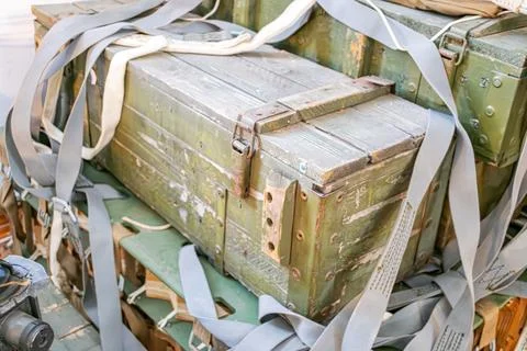 Stack of military ammunition boxes with tape and signs of wear, scattered m.. Stock Photos