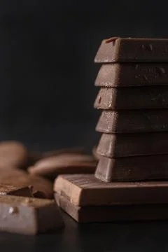 Stack of milk chocolate on dark background. Dessert food background. Stock Photos