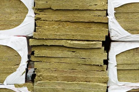 Stack of mineral wool insulation boards in torn plastic wrap shows textured Foto stock
