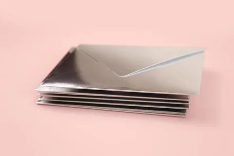 Stack of Mirror or Silver paper festive envelope on pink isolated background Stockfoto's