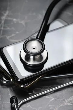 Stack of modern smartphones and stethoscope on black table, closeup 库存照片