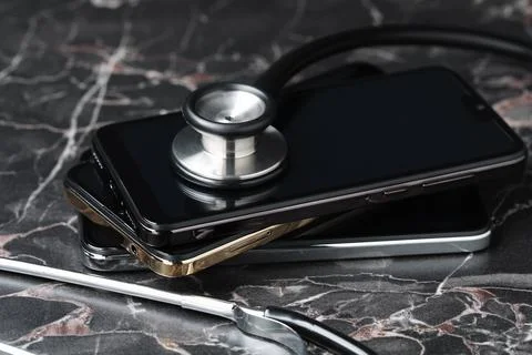Stack of modern smartphones and stethoscope on black table Foto stock