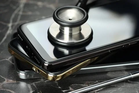 Stack of modern smartphones and stethoscope on black table, closeup 库存照片