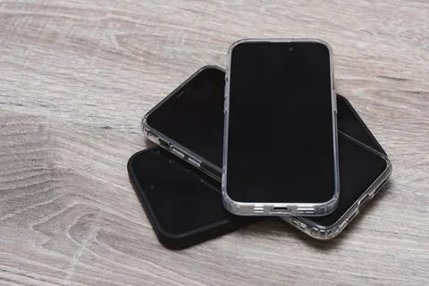Stack of modern smartphones with a protective case on a wooden surface. Con.. Foto stock