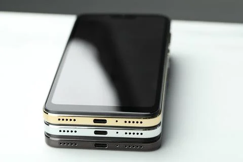 Stack of modern smartphones on white table, closeup 库存照片