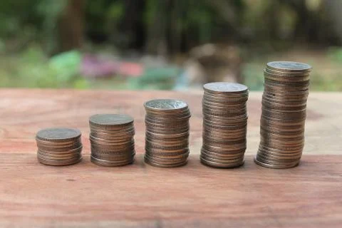 Stack of money coins arranged as a graph on wooden table Stock Photos