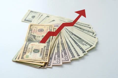 A stack of money with a red arrow pointing upwards Stock Photos