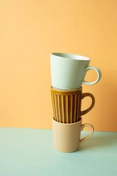 Stack of mug cup on mint green table. orange wall background. copy space S... Stock Photos