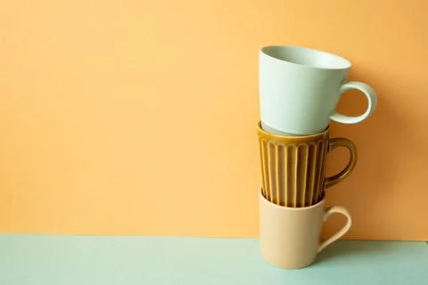 Stack of mug cup on mint green table. orange wall background. copy space S... Stock Photos
