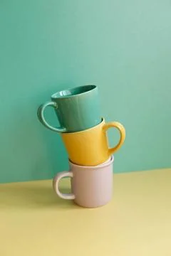 Stack of mug cups on yellow table. green wall background. home interior St... Stock Photos