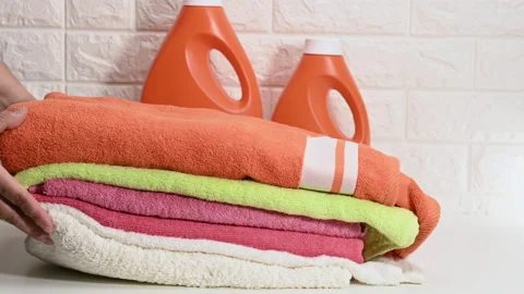 Stack of multi-colored clean dry towels on a white table and plastic bottles wit Stock Footage 169167819