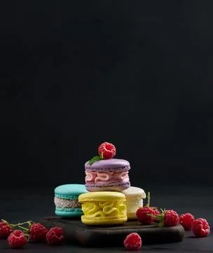 A stack of multi-colored macaroons on a wooden board. Stock Photos