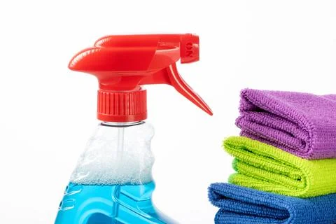 Stack of multi-colored napkins and a bottle with blue cleaning liquid on a white Stock Photos