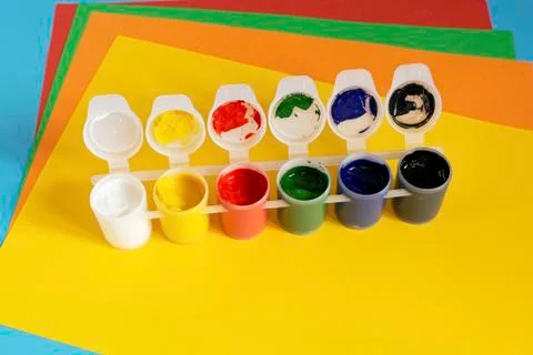 Stack of multi-colored paper and paint for drawing on a blue background. 스톡 사진