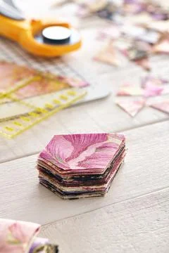 Stack of multi-colored pieces of fabric, ruler, cutting mat, rotary cutter 스톡 사진