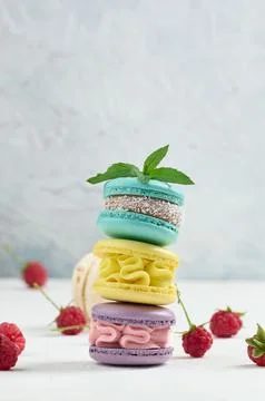 Stack of multicolored macaroons and red raspberries on a white background Stock Photos