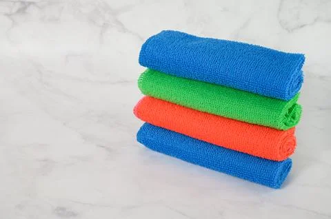 Stack of multicolored microfiber cloths on a light marble background. Stock Photos