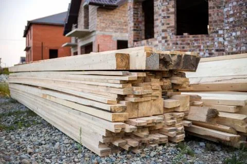 Stack of natural brown uneven rough wooden boards on building site. Industria Fotos de archivo