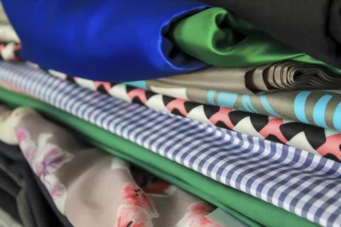 A stack of natural silk fabrics of different colors and textures. Stock Photos